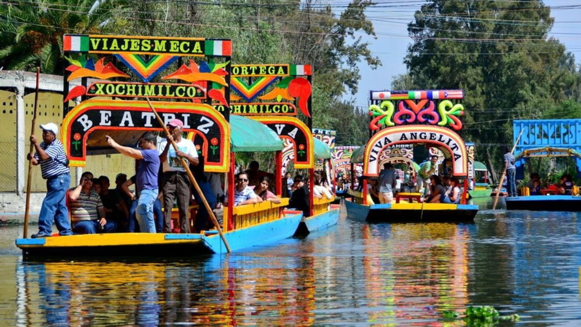 a group of people riding on the back of a boat with Xochimilco in the background